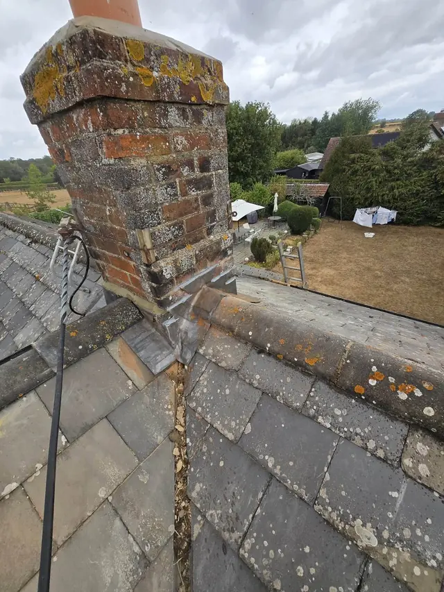 Brick chimney stack against the sky above a slate roof