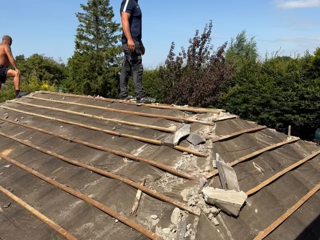 Roofer at the ridge of a roof being stripped back